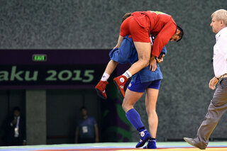 Gouden medaillewinnaar Stsiapan Papou draagt zijn geblesseerde tegenstander van de mat