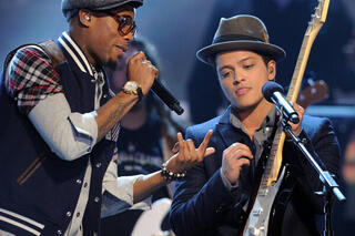 Bruno Mars op het podium, met gitaar in de hand, naast B.O.B.