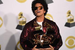 Foto van Bruno Mars op de uitreiking van de Grammy Awards, zes Grammy's in zijn armen gestapeld