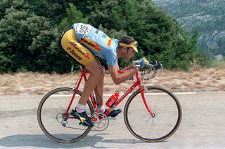 Foto van Eros Poli die dubbelgeplooid op zijn fiets zit.